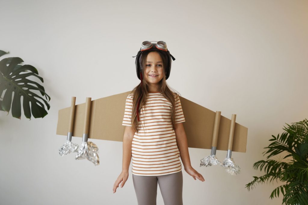 Girl with cardboard rocket wings. 