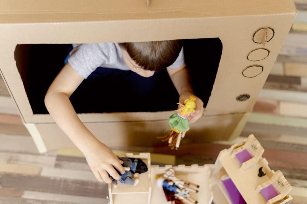 Young boy playing in cardboard tv. 