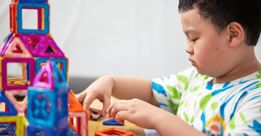 Young boy building with magnetic tiles. 