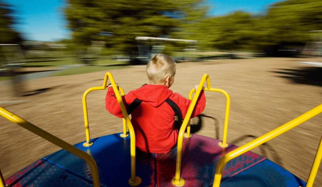 Young boy playing on a merry-go-round.