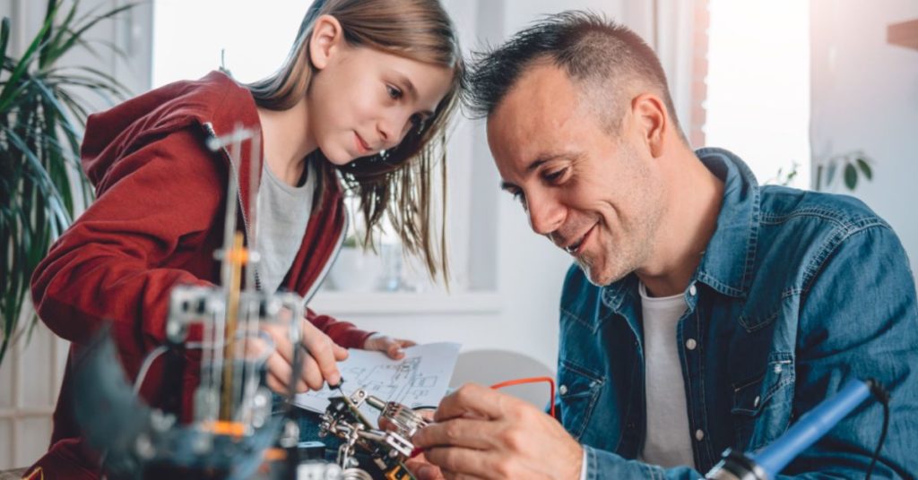 Parent and child building a robot. 