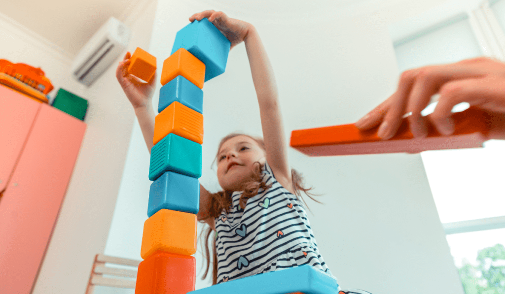 Girl stacking tall tower of blocks. 