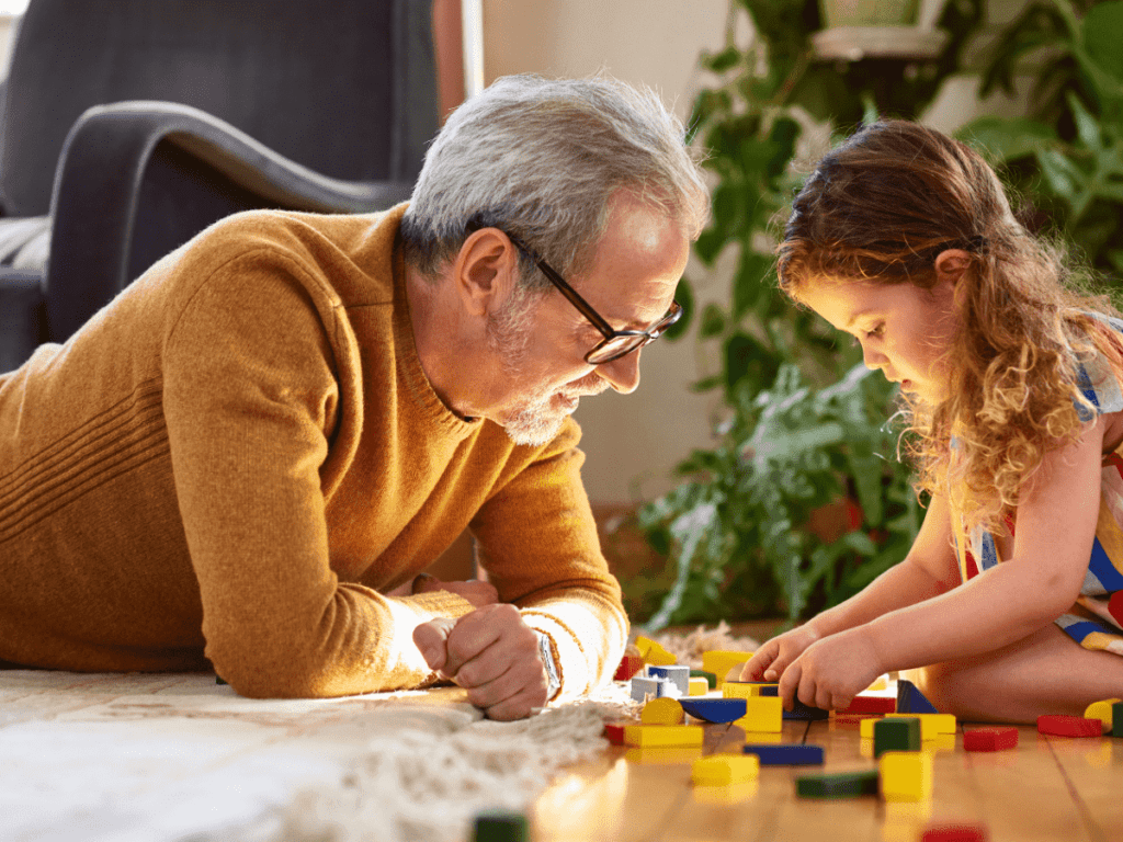 Grandfather playing with blocks with granddaughter. 
