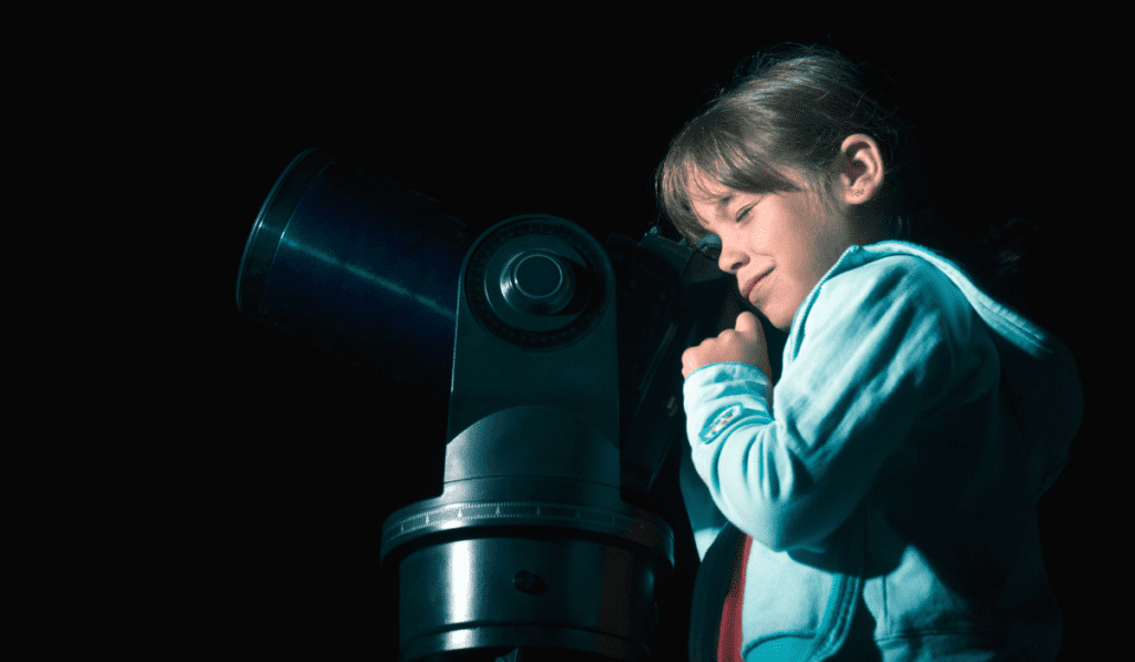 Girl observing the stars and planets with a telescope. 