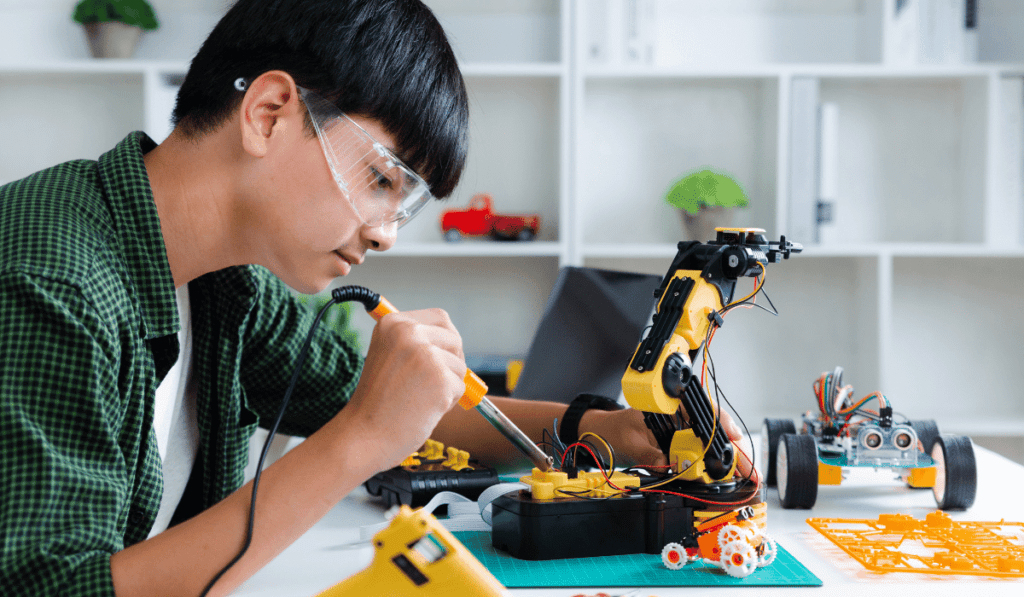 Teen boy soldering assembling a robot kit.