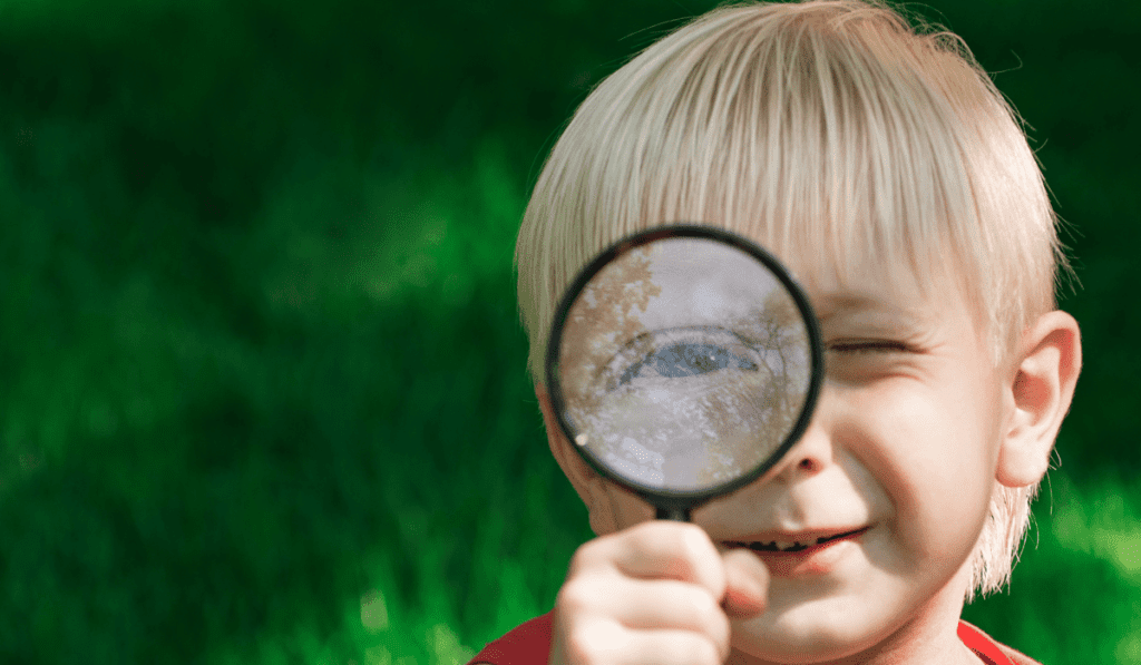 Boy looking through a magnifying glass.