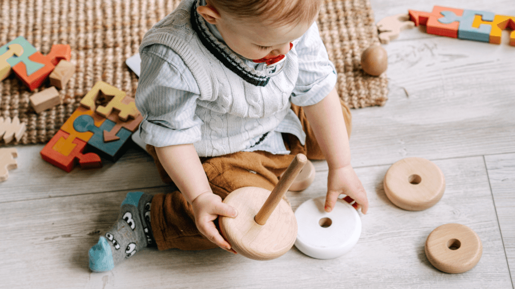 Toddler playing with wood stacking toy. 